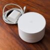 Google Wifi NLS-1304-25 路由器與裂損電源線 Google Wifi NLS-1304-25 AC1200 Mesh Wi-Fi 路由器,旁為線材裂損的原廠電源供應器