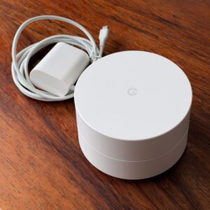 Google Wifi NLS-1304-25 路由器與裂損電源線 Google Wifi NLS-1304-25 AC1200 Mesh Wi-Fi 路由器,旁為線材裂損的原廠電源供應器